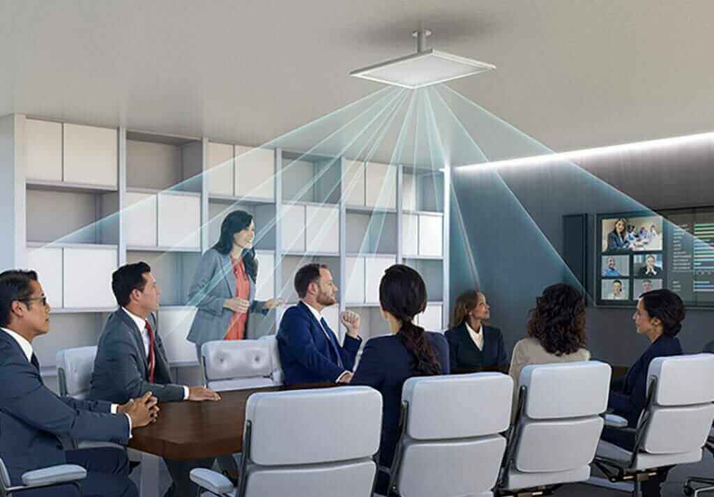 Conference room with diverse professionals, overhead microphone system, and video conferencing screen.
