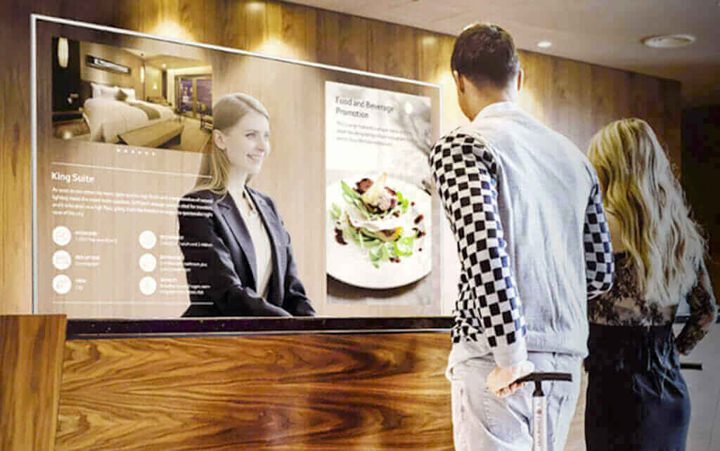 Interactive digital signage at hotel lobby showcasing room and dining options, with couple viewing display.